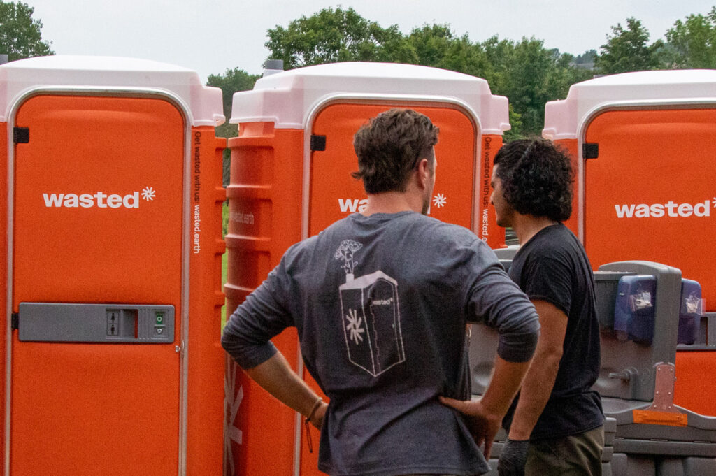 Two male members of the wasted team onsite with porta potties